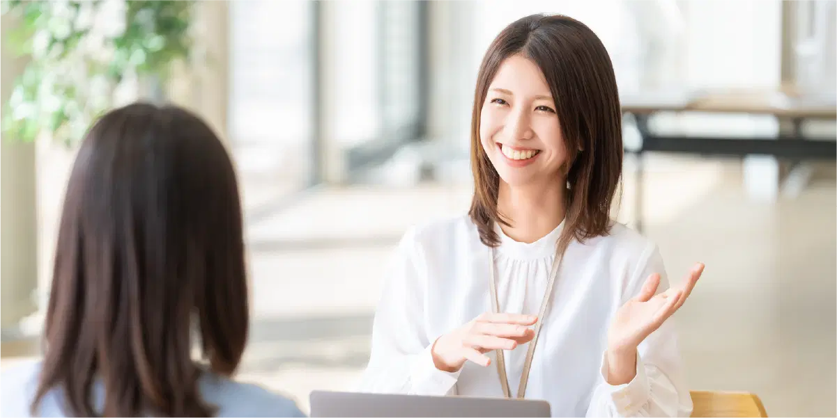 白い服の女性が手も使って笑顔で話している