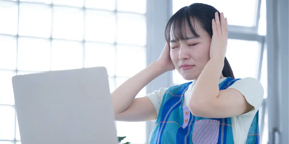 PCの前で頭を抱えて悩む女性