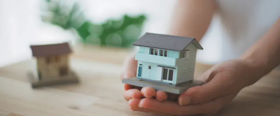 戸建ての家のミニチュアを手で包む様子
