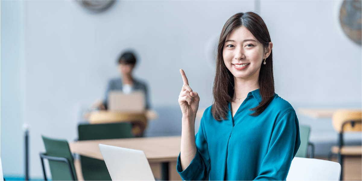 緑の服を着た女性が人差し指を立てて笑っている