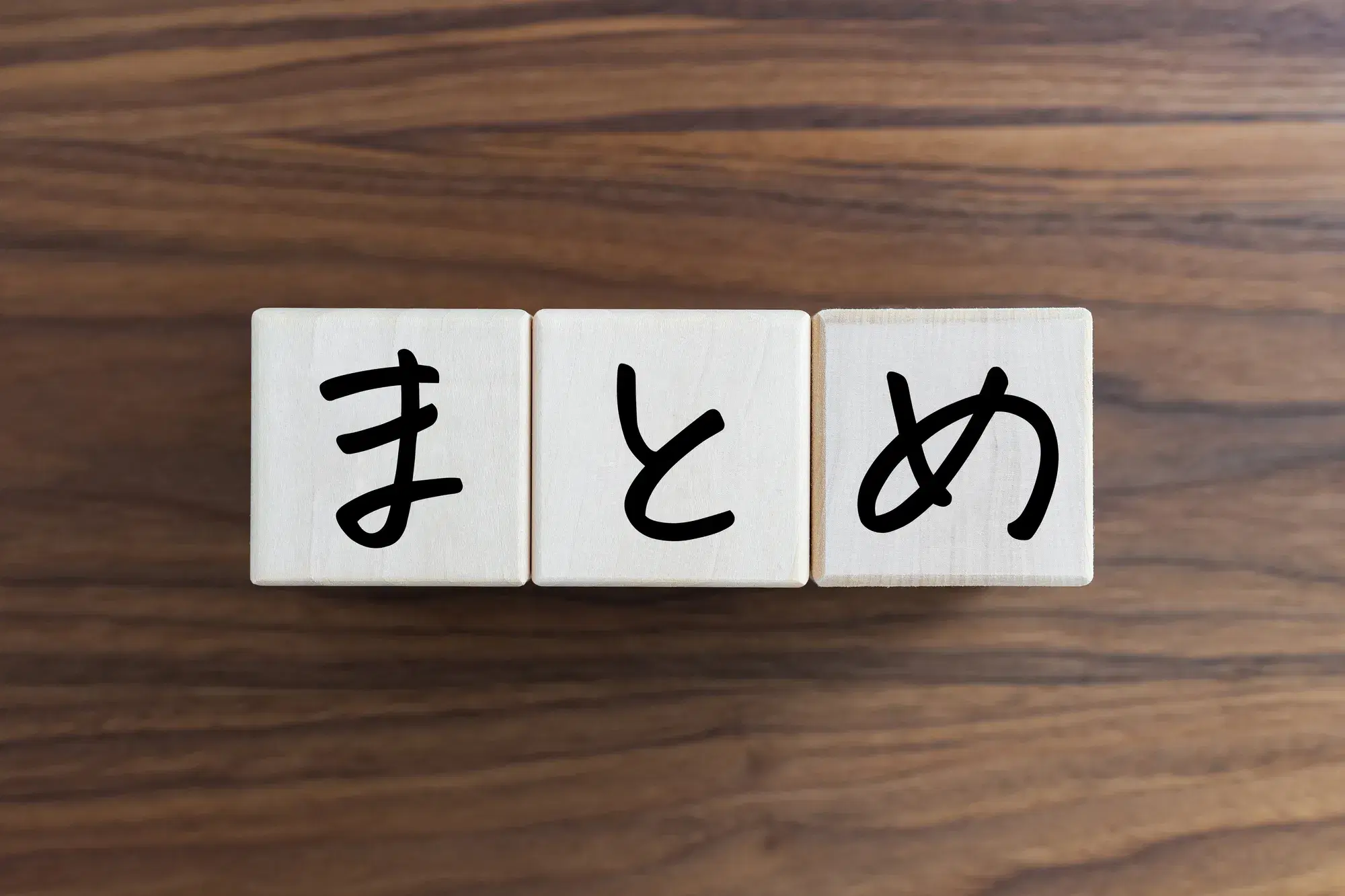 木目のテーブルの上に「まとめ」と書かれた3つの木製ブロックが並べられている様子が写っている。