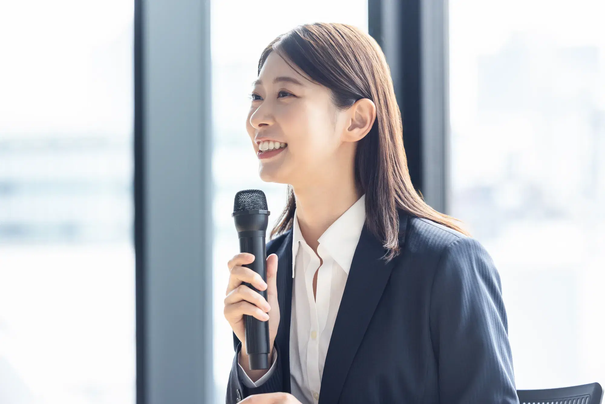 スーツを着た女性がマイクを持って話している