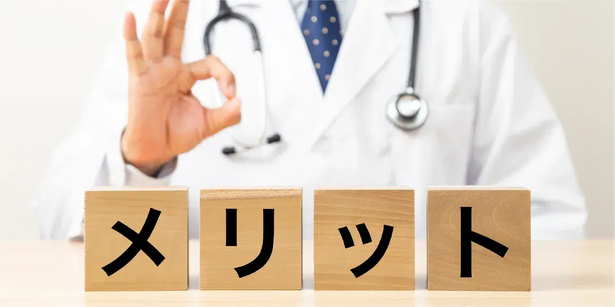 手でOKサインを出している医療職員男性とメリットと書かれた木のキューブ