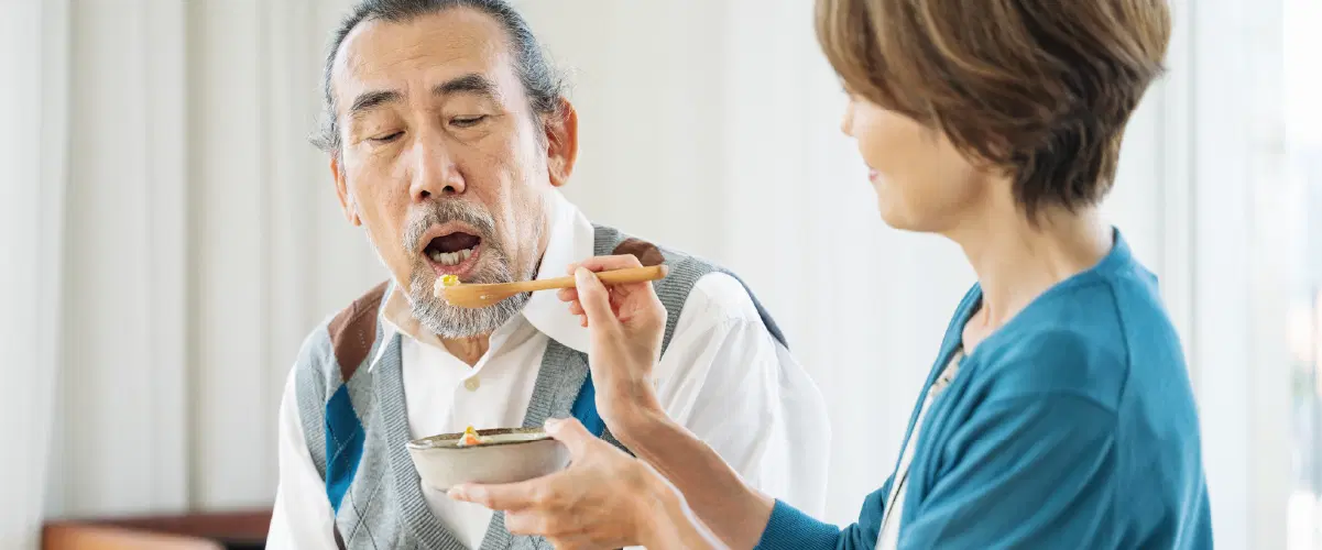 高齢者に食事のサポートをしている女性