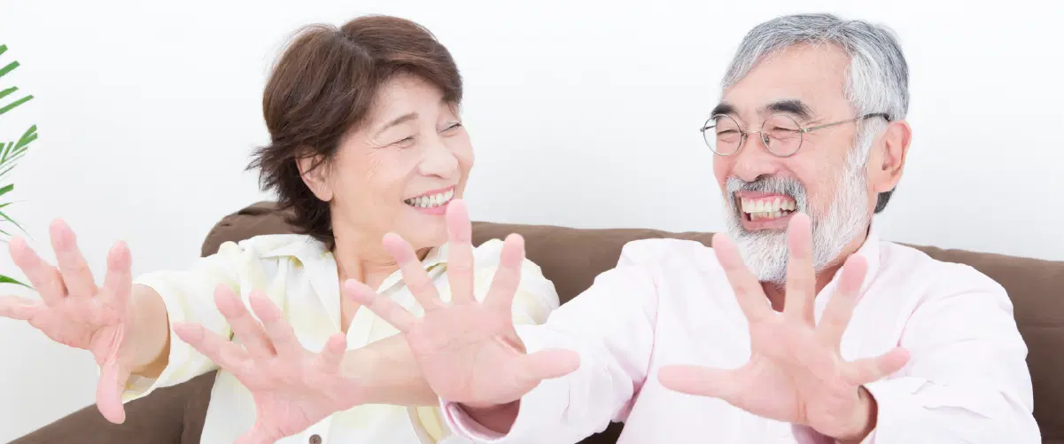 両手を前に出し笑顔の高齢の男女