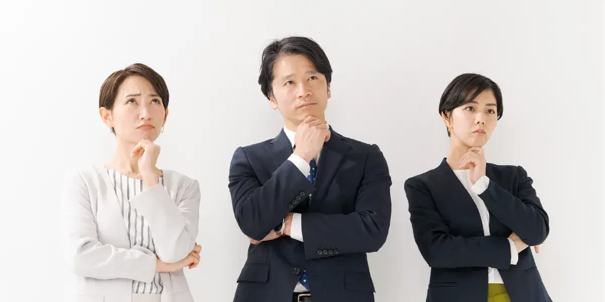 腕を組み考える様子のスーツを着た男女