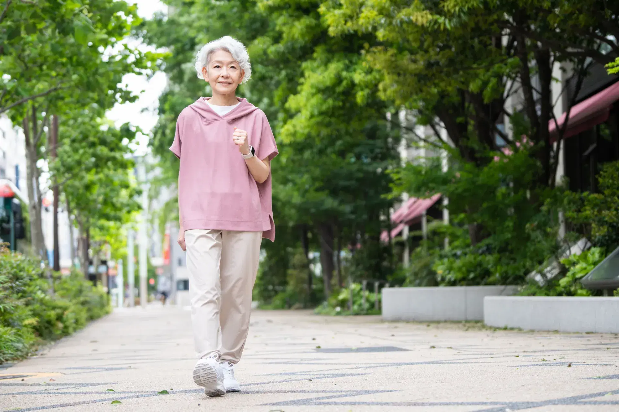 ピンクの服を着た老人女性が散歩をしている