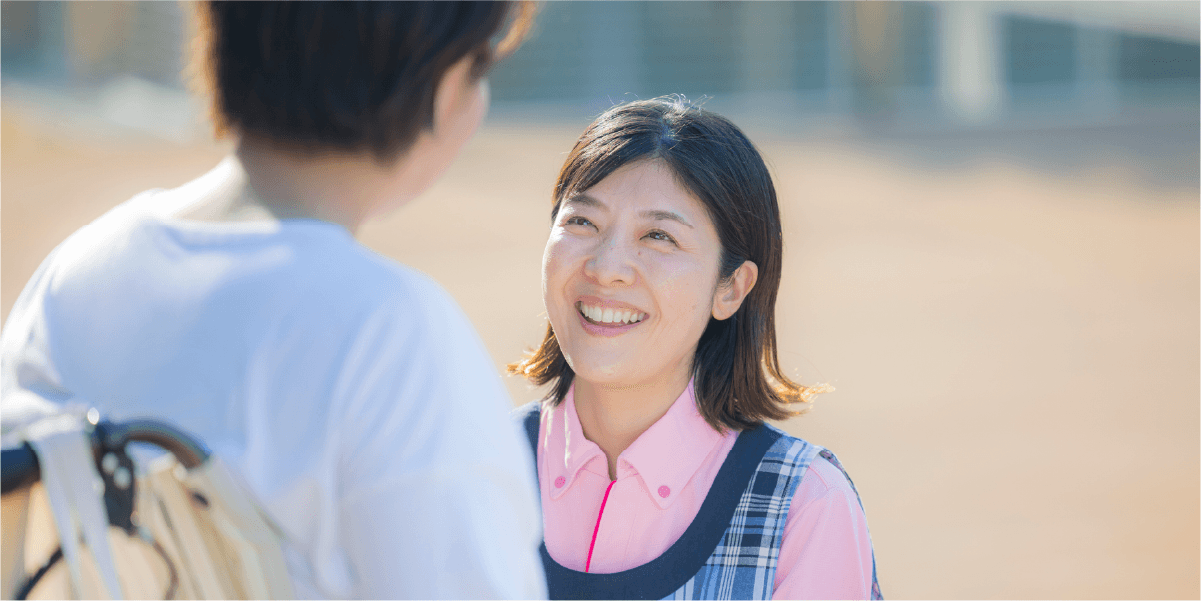 しゃがんで車椅子の女性と笑顔で話す女性