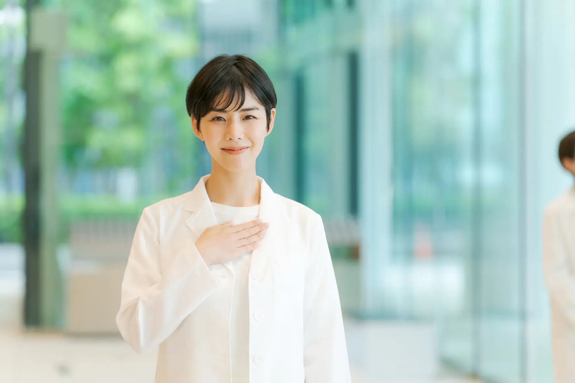 手を胸にあてた白い服を着ている女性