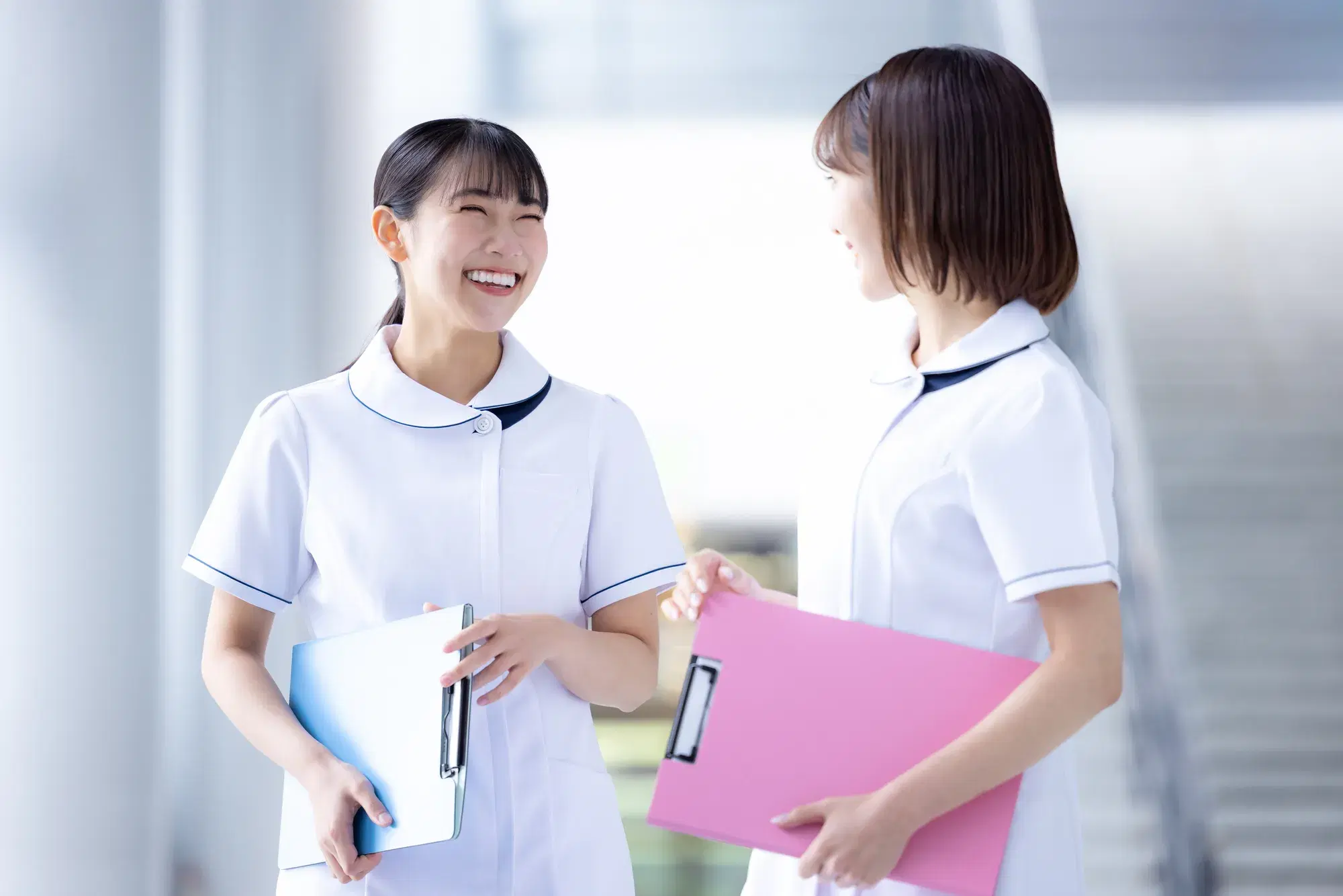 白い白衣の女性二人が話しながら笑っている