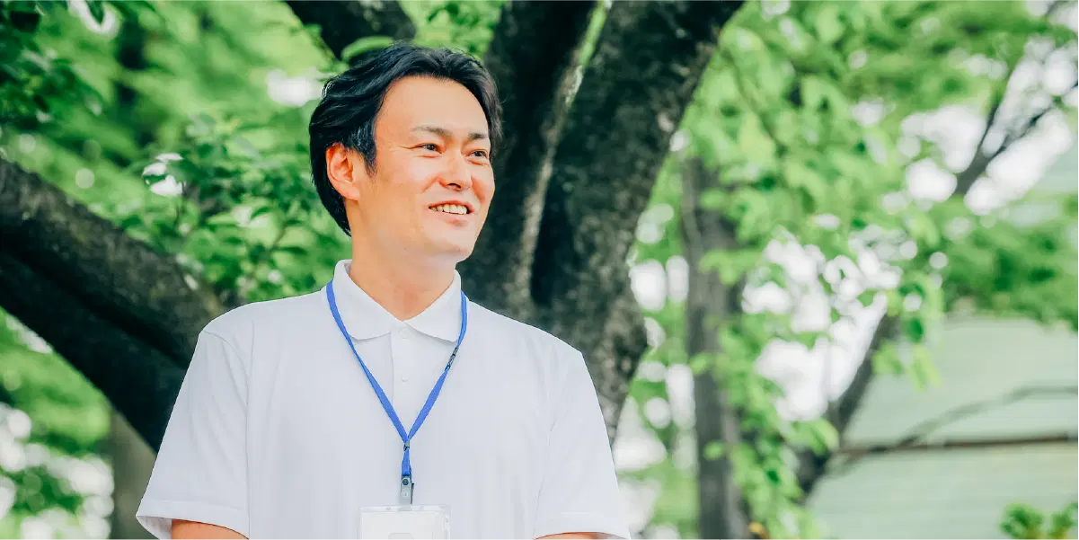 気を背景に笑う白い服を着た男性