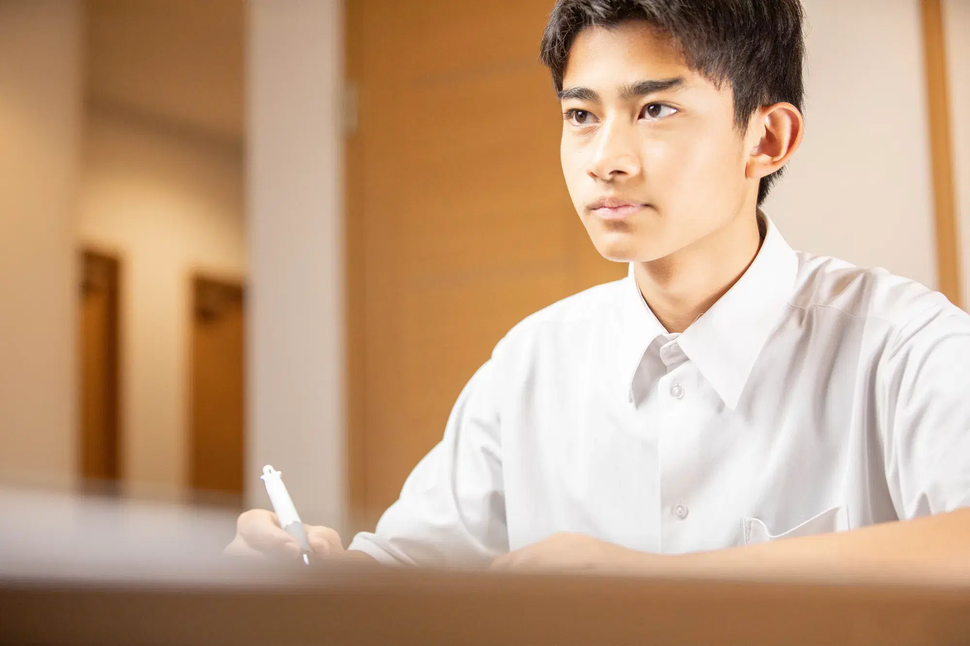 白い服装の男性が右手に白い筆記用具をもって勉強