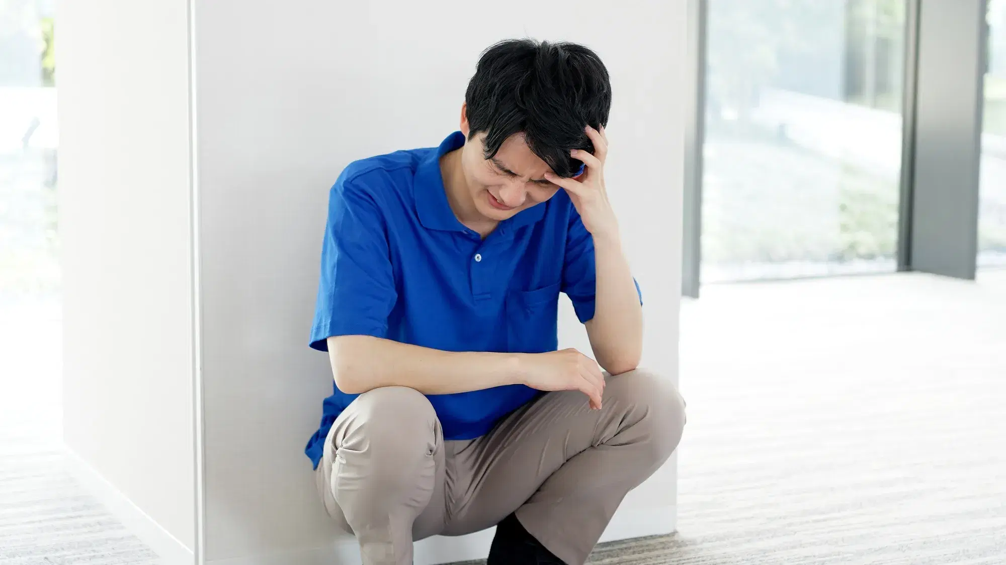 白い柱に座ってもたれかかる男性