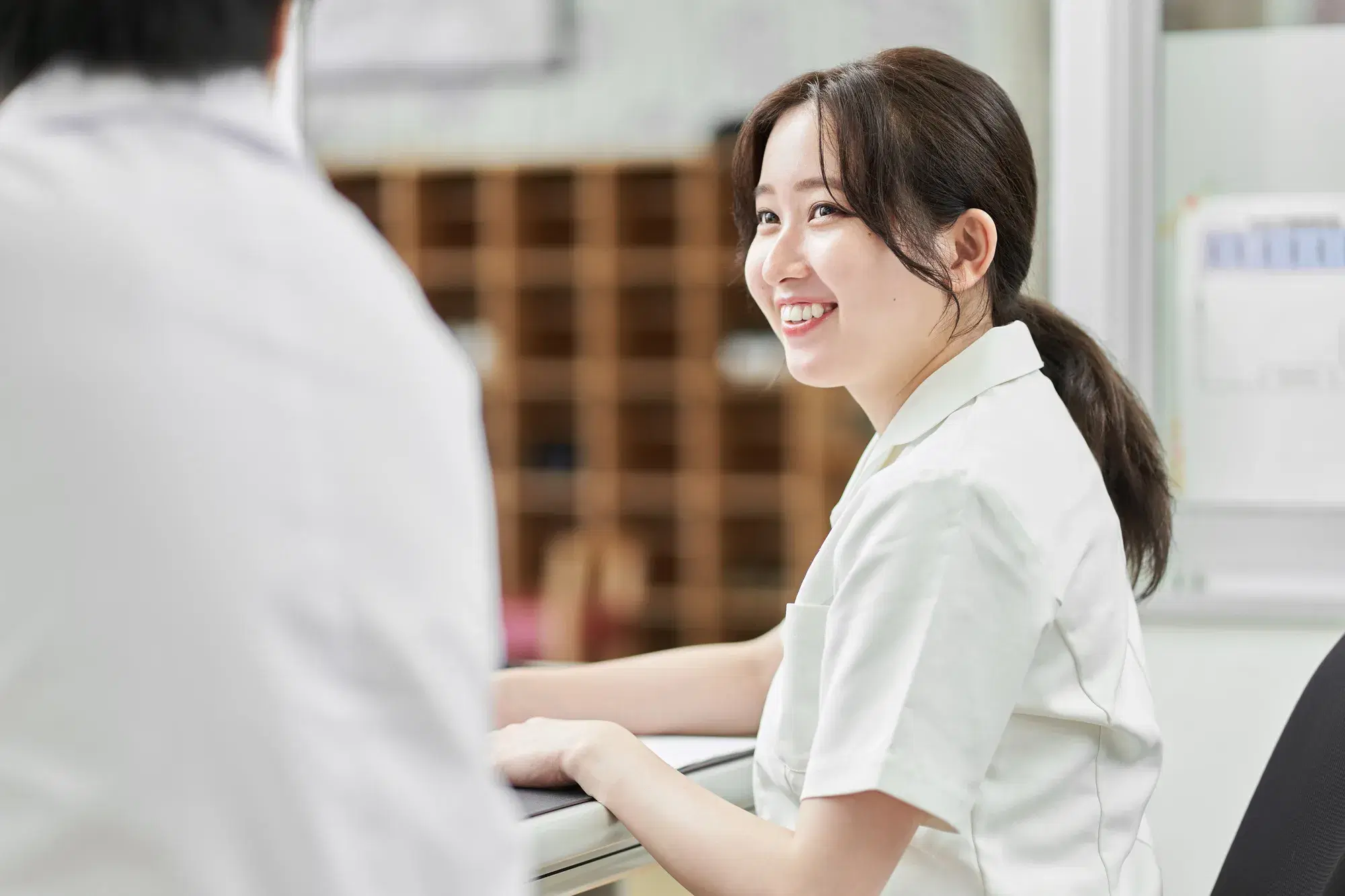 白い服を着た女性が隣の人間と会話