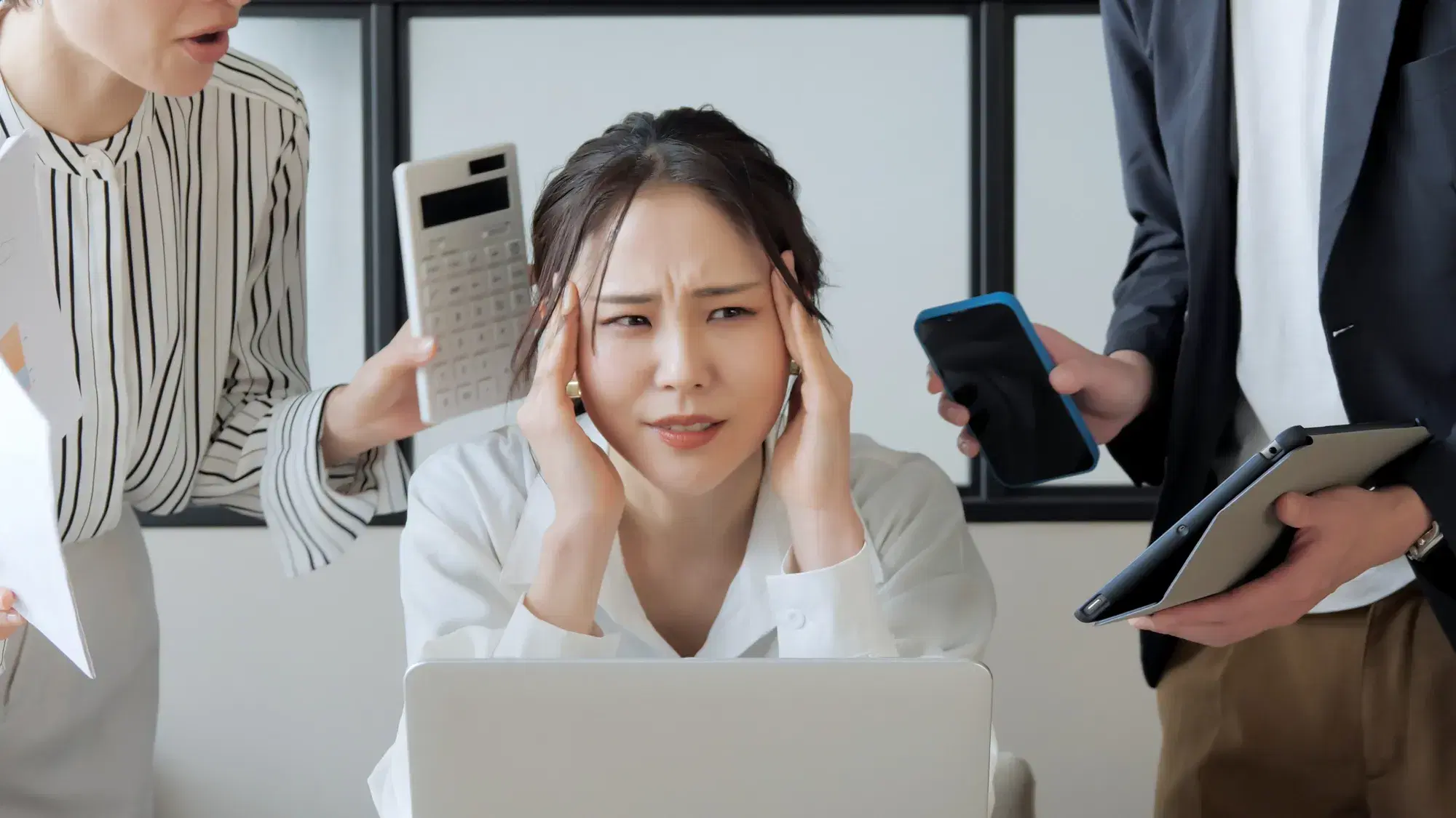 黒色の縦縞模様が入った服を着ている電卓を持った女性と黒色のスーツを着た携帯とバインダーを持った男性が白い服を着た女性を責める