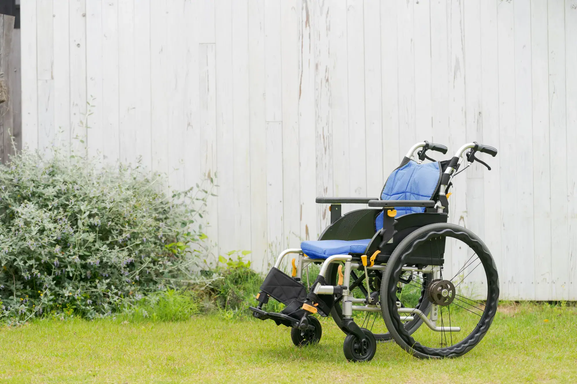 背景が白色の壁で手前に座席が青色のシートの車椅子