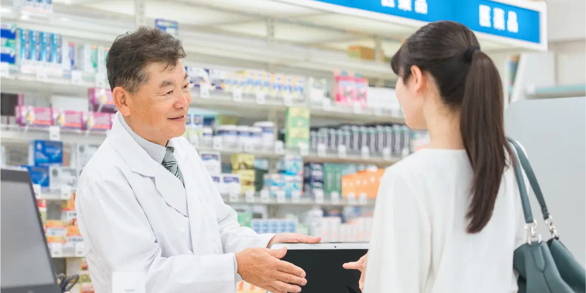 客の女性に薬の説明の行う薬剤師