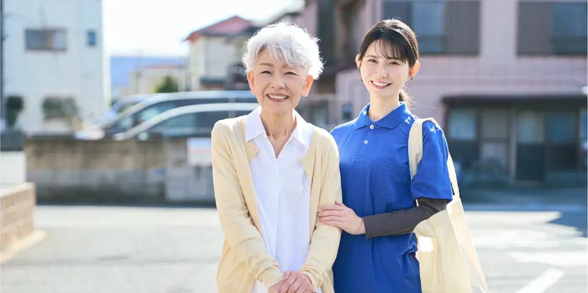 年配の女性を青い服の女性が支えている