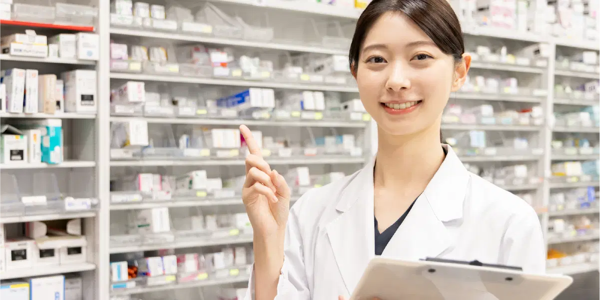 バインダーを持ち人差し指を立てる薬剤師の女性