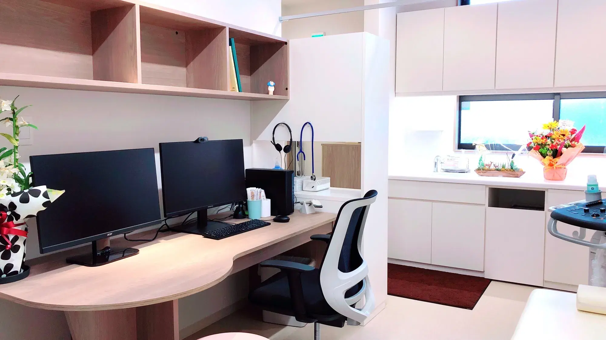 パソコンが二台と台所のある部屋が映っている。