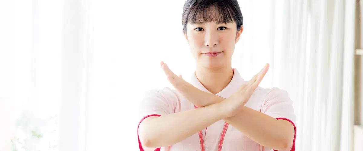 胸元で×を作るエプロンを付けた女性