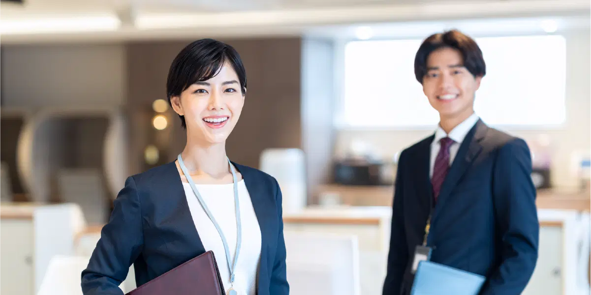 スーツを着てバインダーを持ち笑っている男女