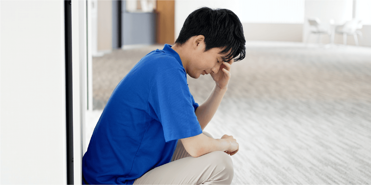 青い服を着た男性が座り込んで泣いている