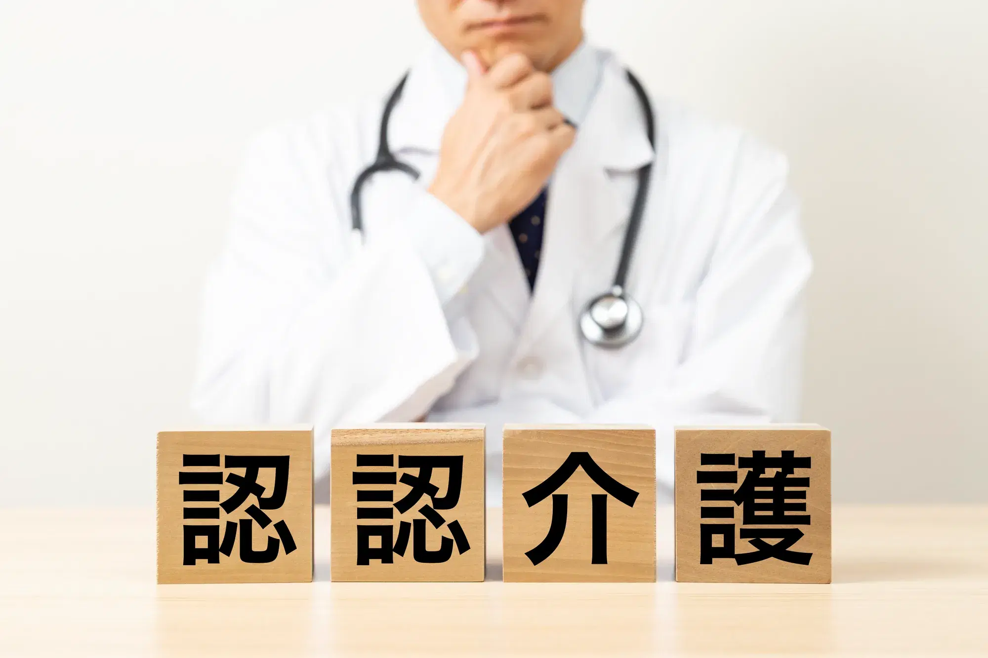 白衣を着た男性と認認介護と書かれた木材ブロック
