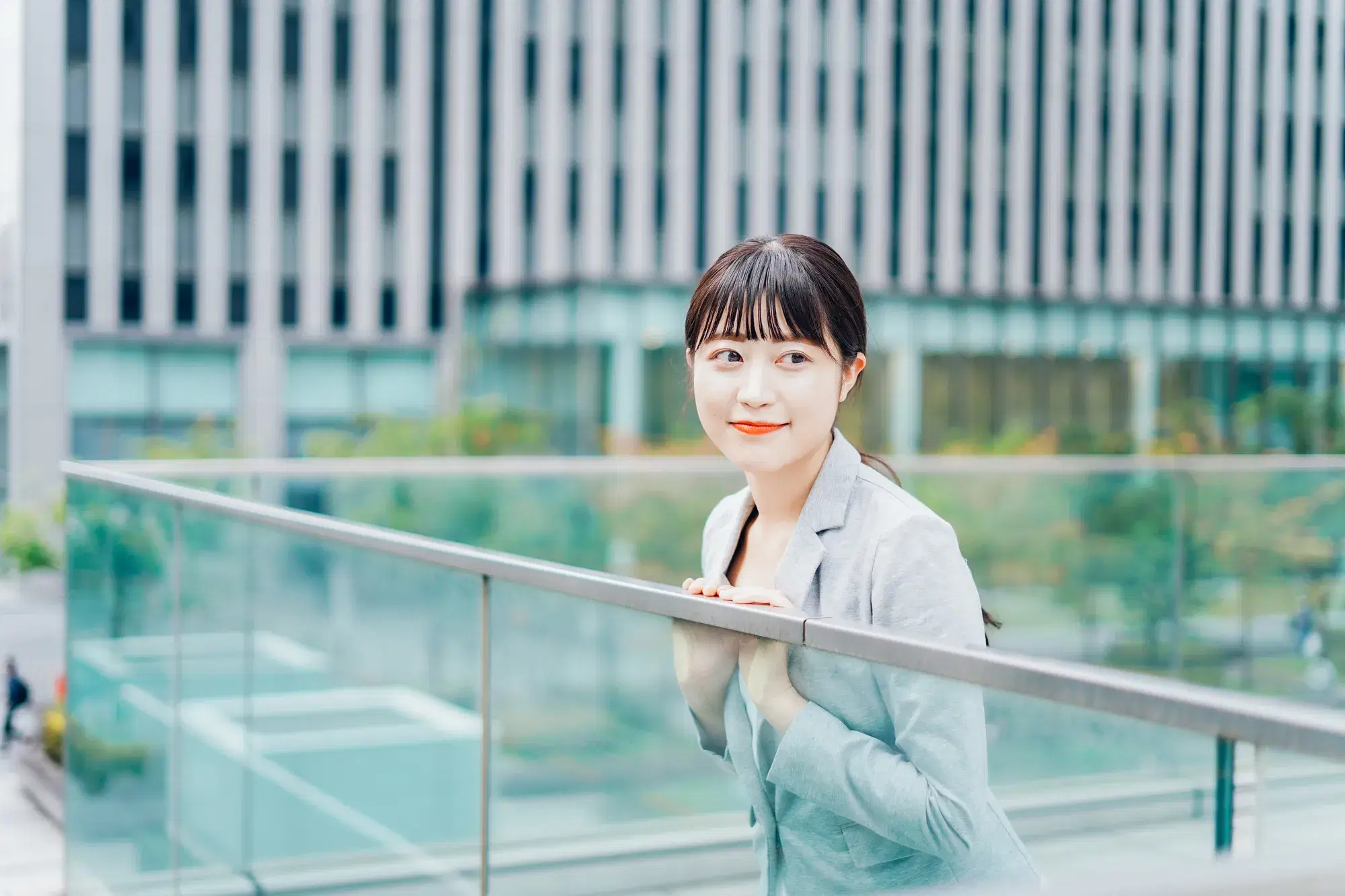 ガラス張りの屋外で外を観察する灰色のスーツを着た女性