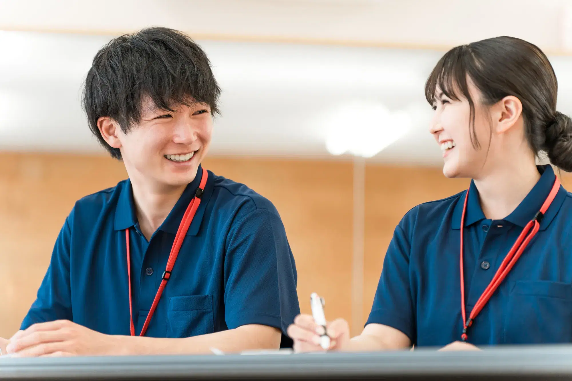 紺色の服を着た男女が笑顔で会話