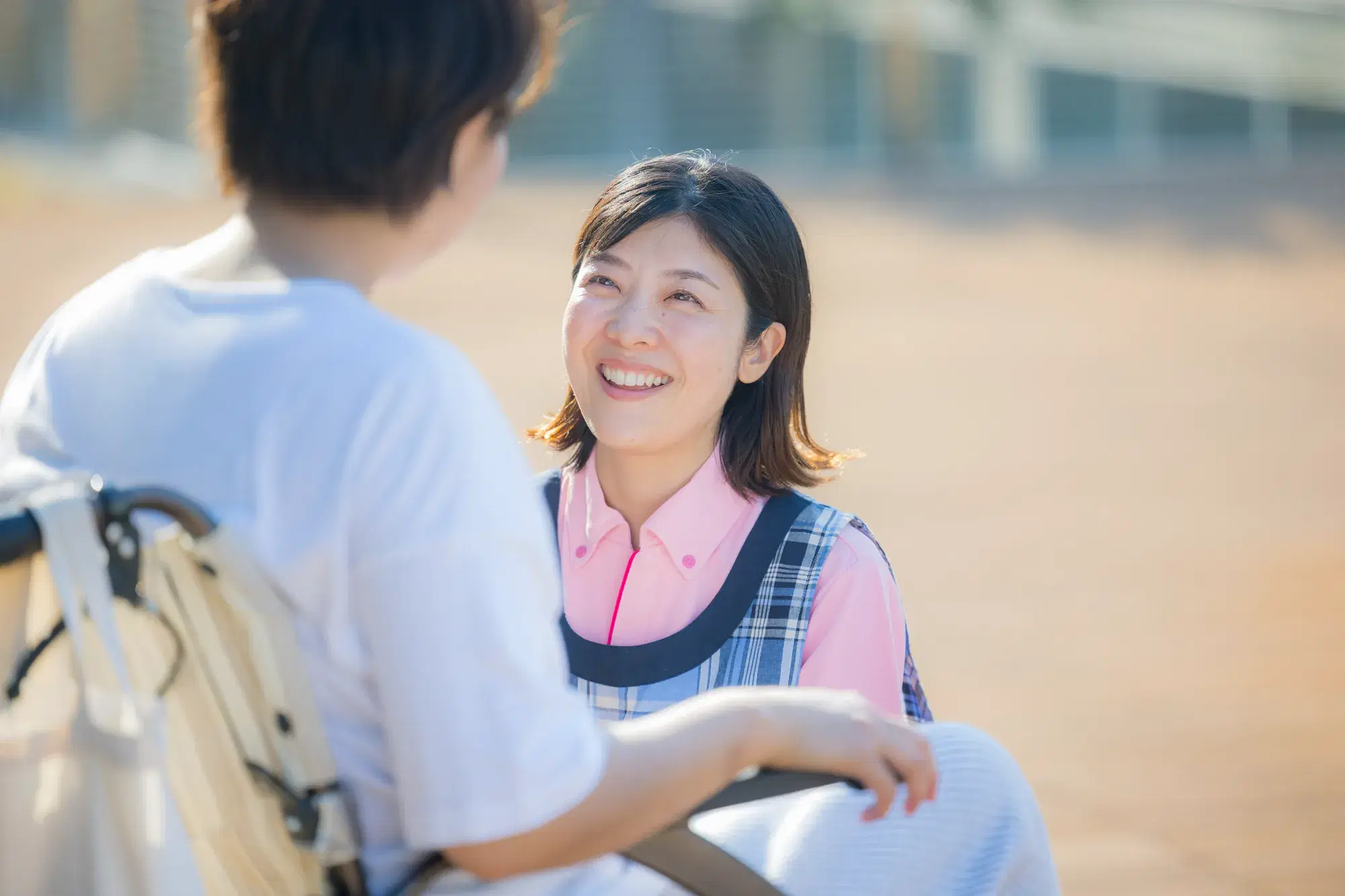 しゃがんで車椅子の女性と笑顔で話す女性
