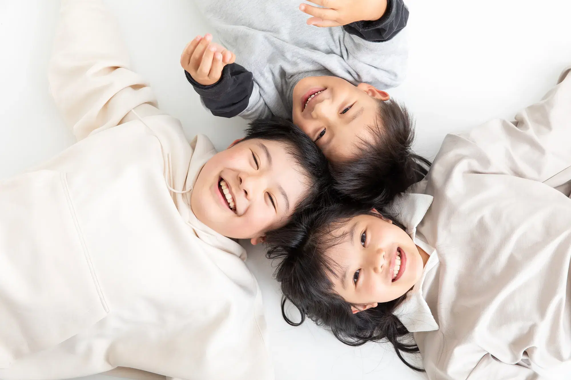 複数の子どもが頭をくっつけながら寝そべっている