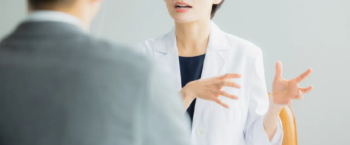 白衣を着ている女性がスーツの方に話をしている