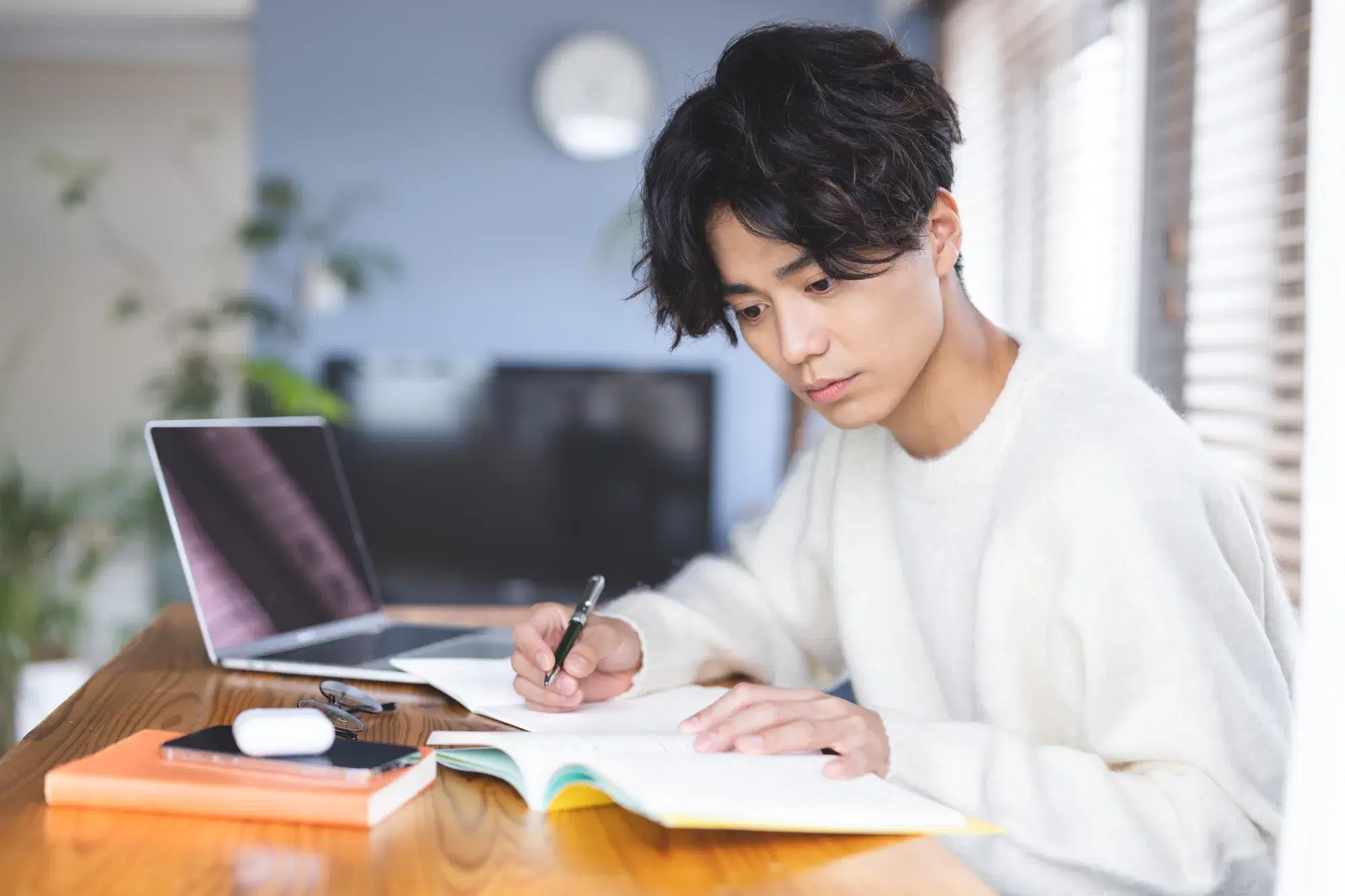 男性がパソコンと参考書を使って勉強している