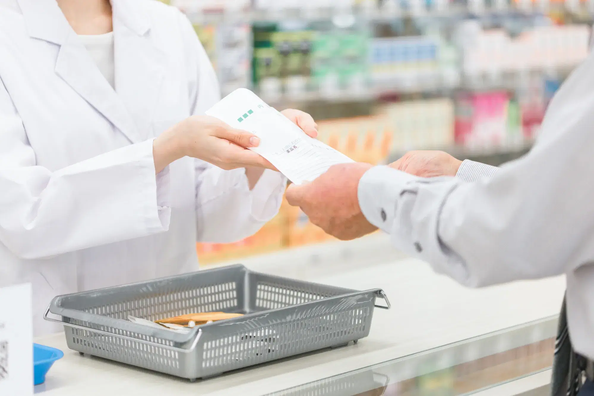 薬剤師が薬を灰色の服を着た男性に渡している