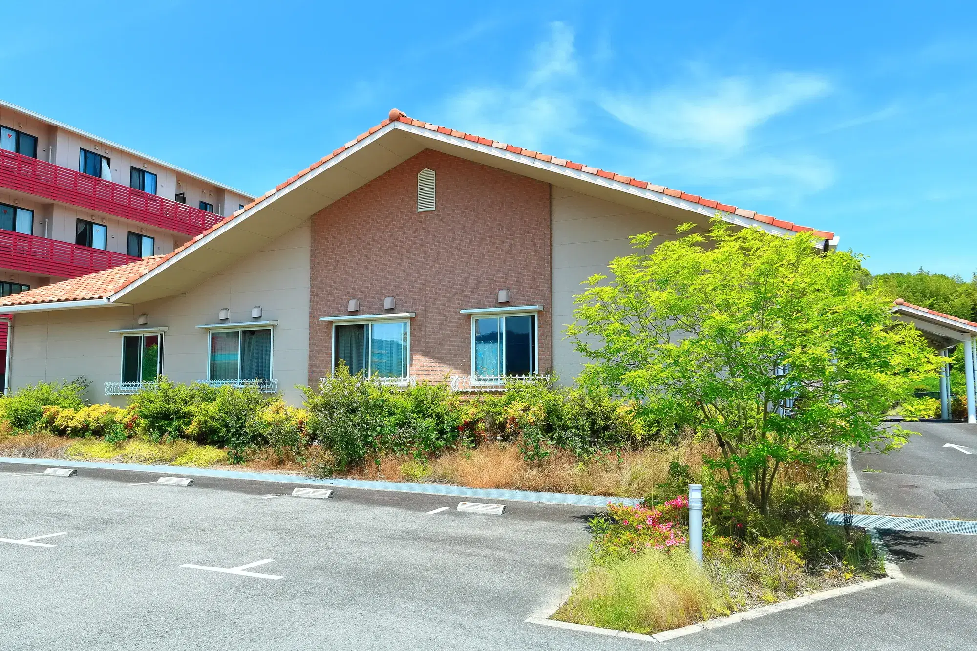 駐車場と庭があるオレンジ色の屋根の建物が写っている。
