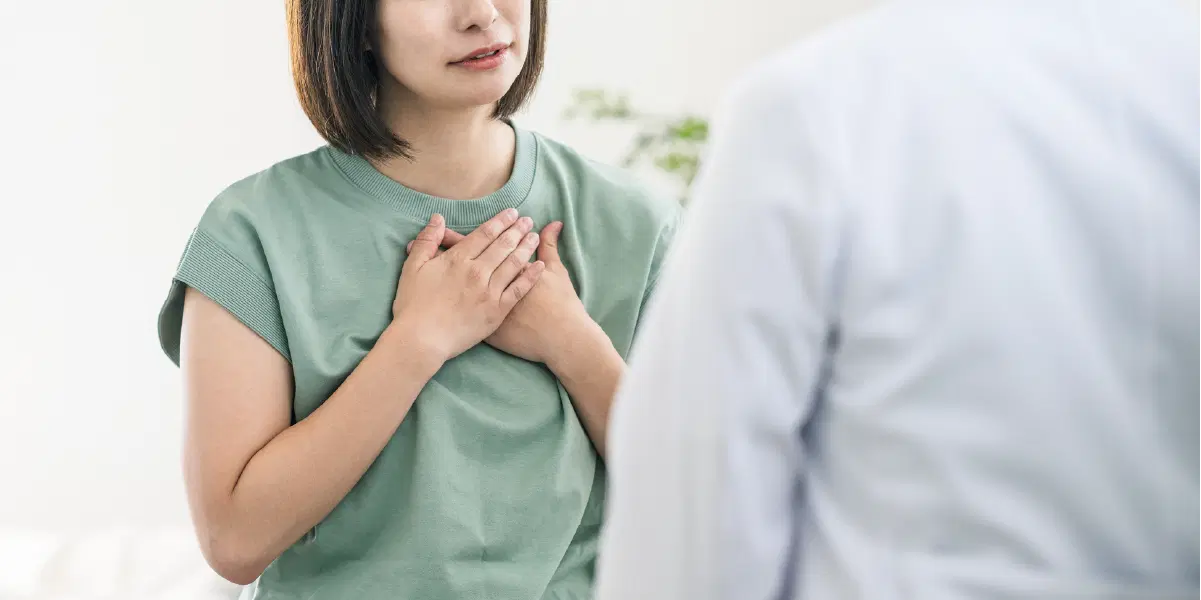 話しながら、胸に手を当てている女性