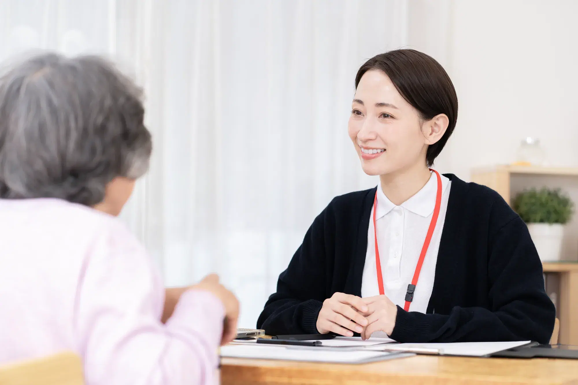 黒いカーディガンを羽織った人が老人の話を聞いている