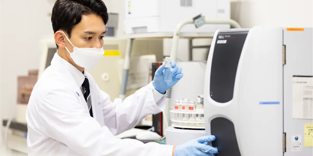 分析機器を用いて試験管内の物質を検査する臨床検査技師