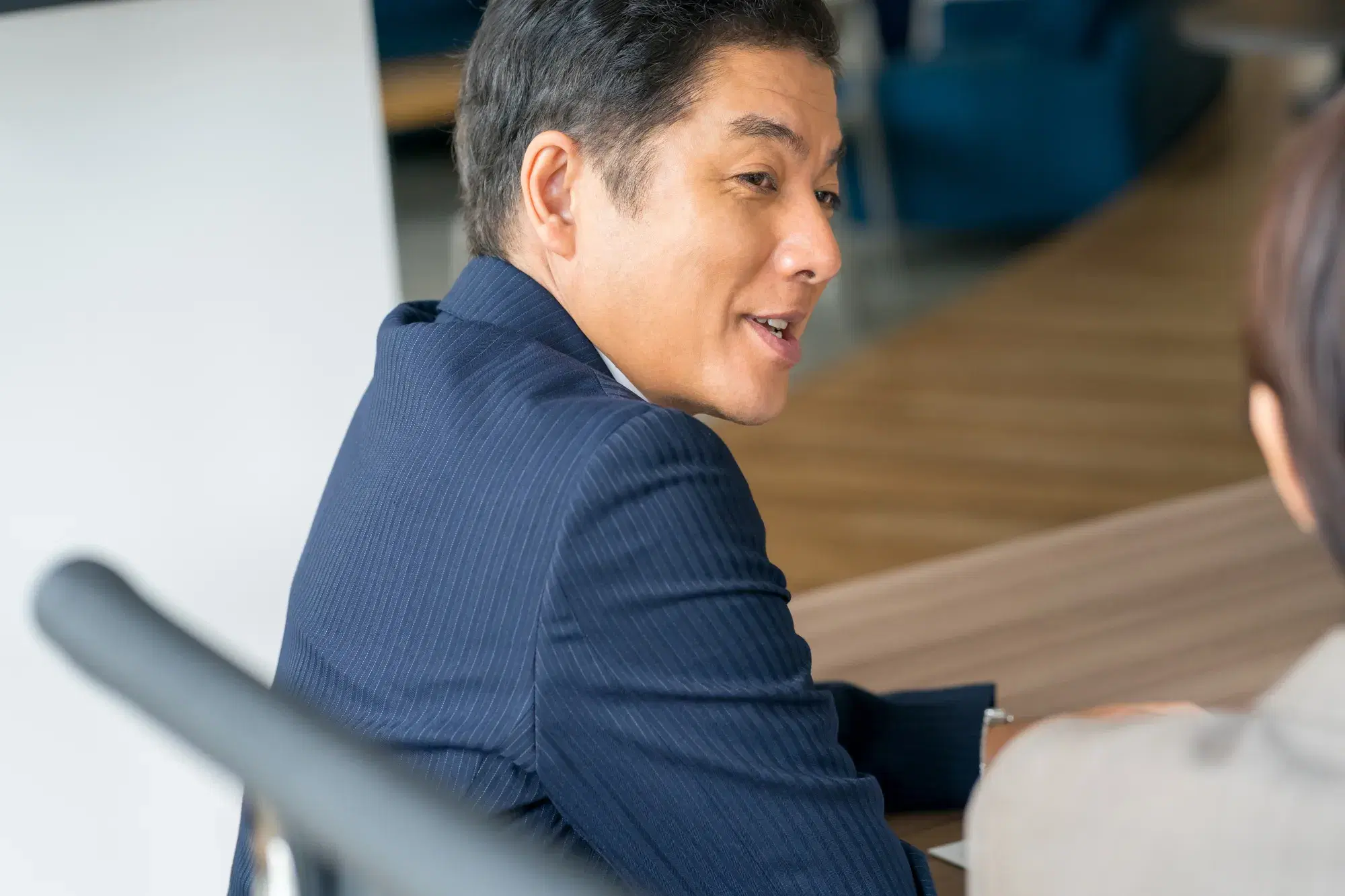 紺色のスーツを着た男性がとなりの灰色の服を着た男性と会話