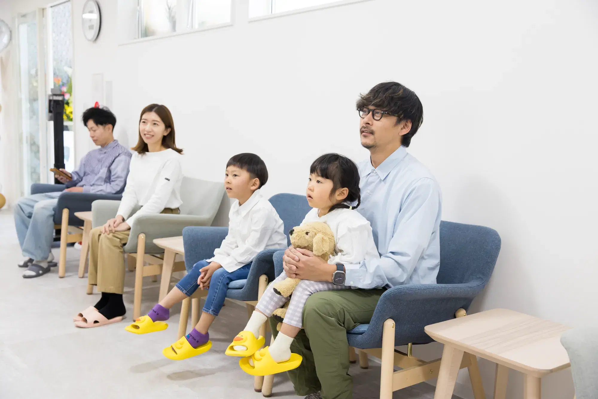 青い椅子に座っている親が膝に子どもを乗せて待機