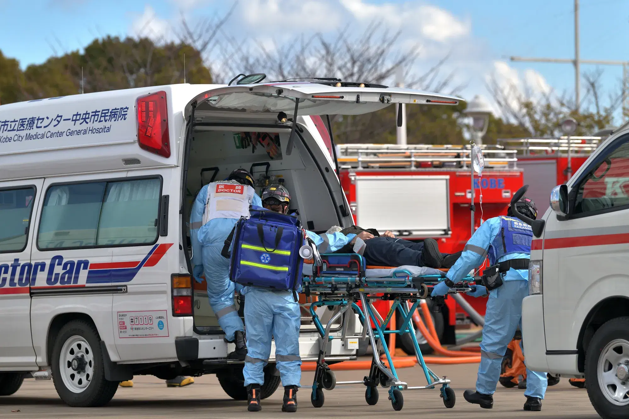 救急車に患者を搬送している青色のバックを背負った水色の服を着た救急隊員