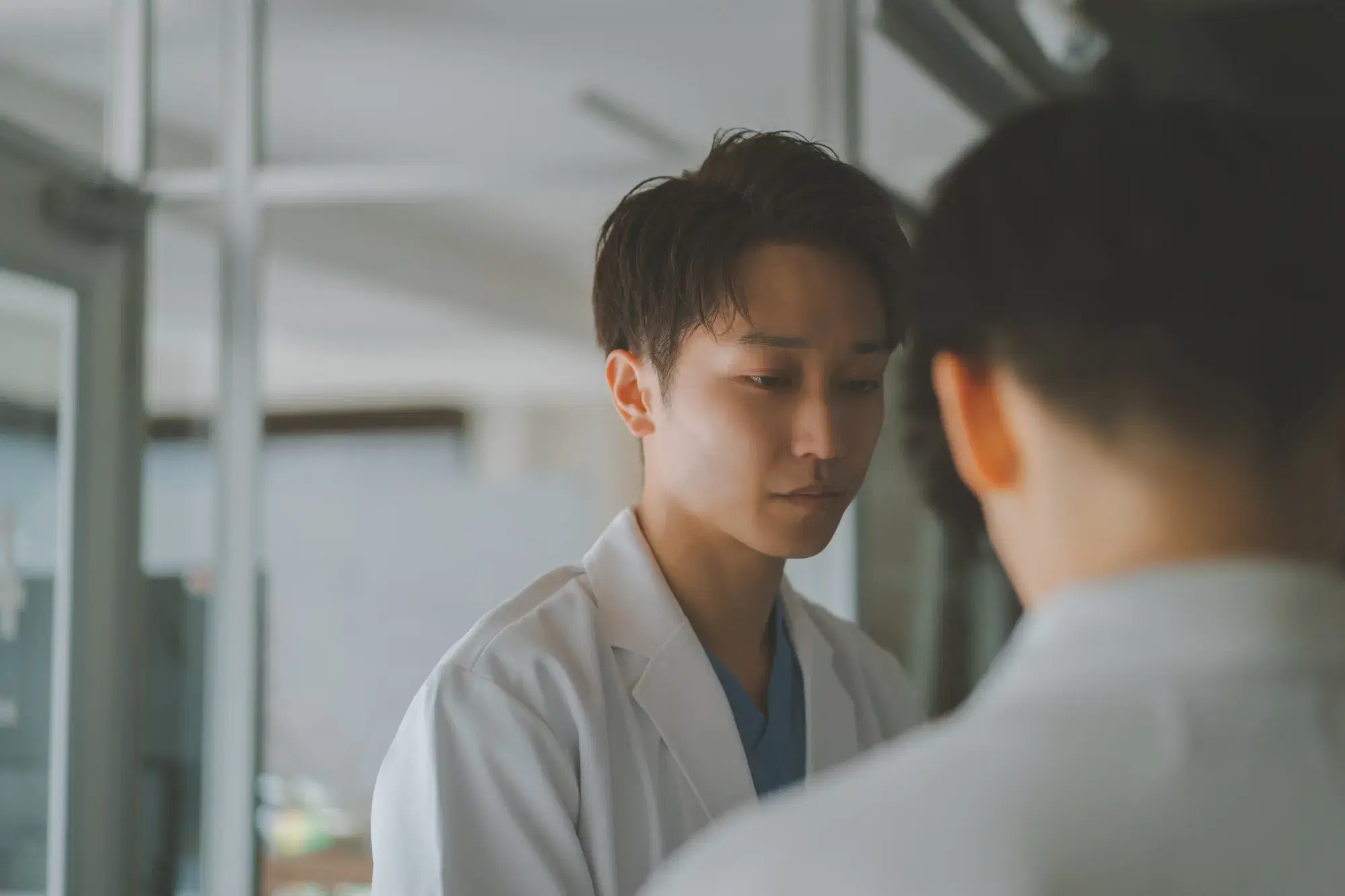 白衣を着た男性と白衣を着たうつむいている人間