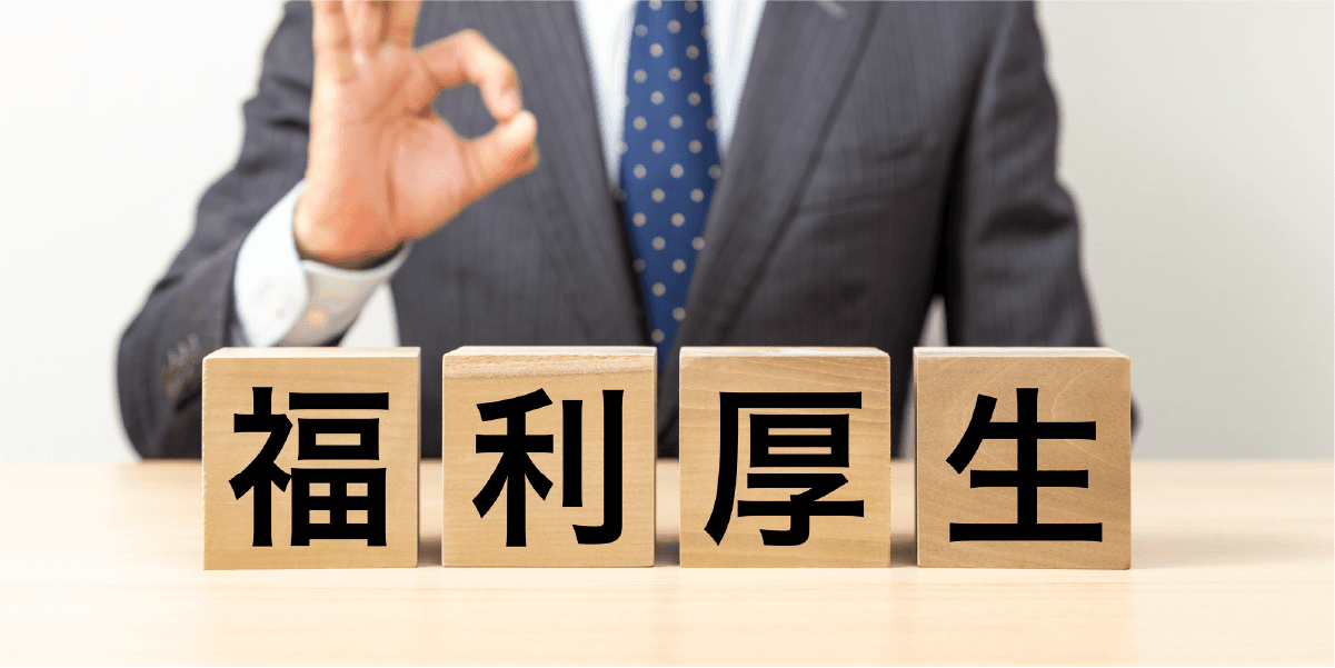 福利厚生と書かれた木のキューブと指で丸を作るスーツの男性