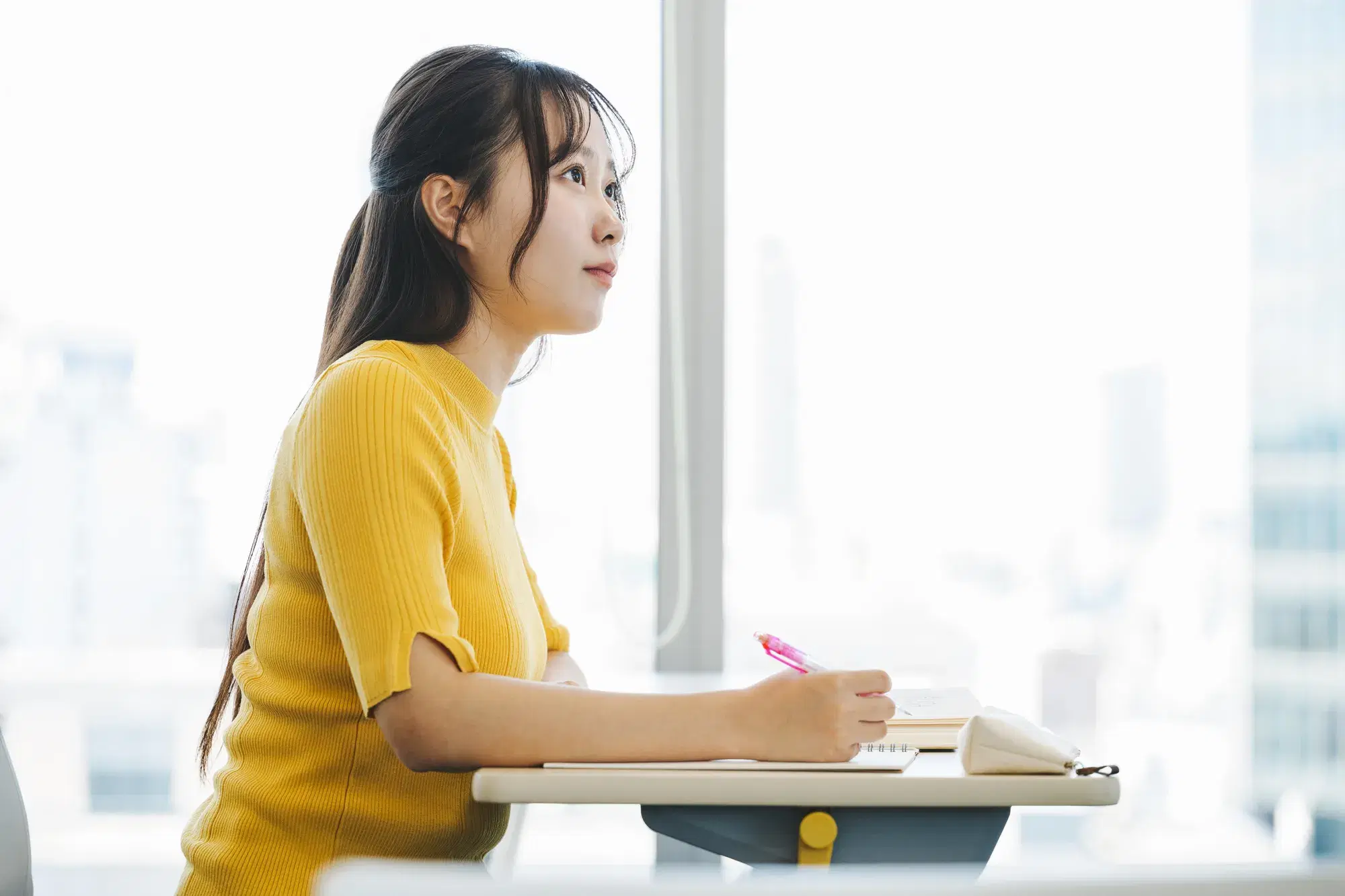 黄色い服を着た女性が座って勉強している