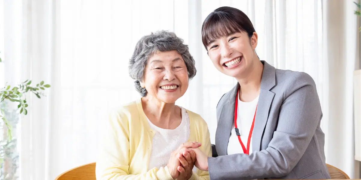 笑顔で手を取りあう年配の女性と若い女性