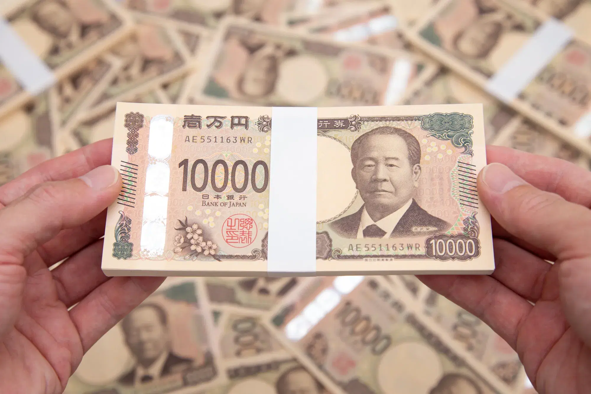 画面いっぱいに束になった一万円札から両手で一つ取る