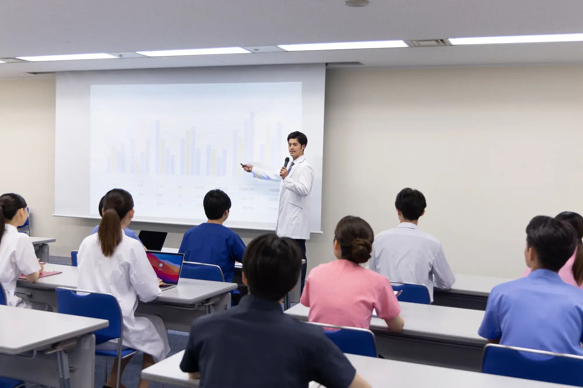 白衣を着た男性が講義をしている