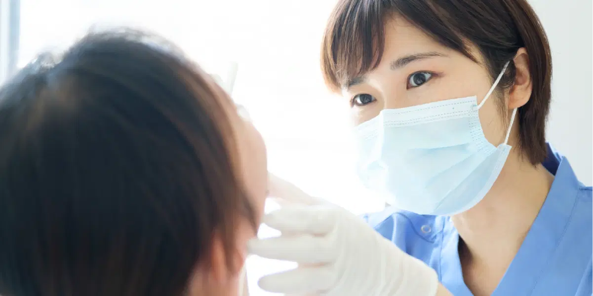 口腔を確認して理療を行う歯科医療のスタッフ女性