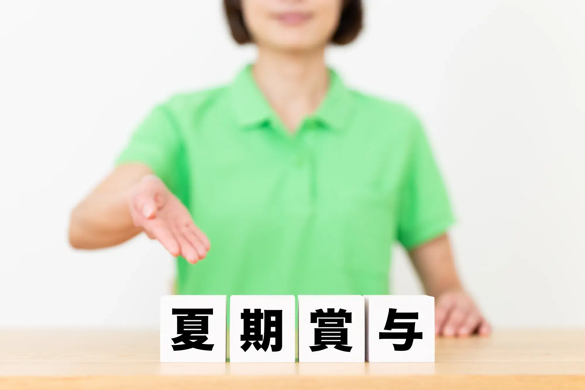 緑の服を着た女性が夏期賞与と書かれた白いブロックを指差し